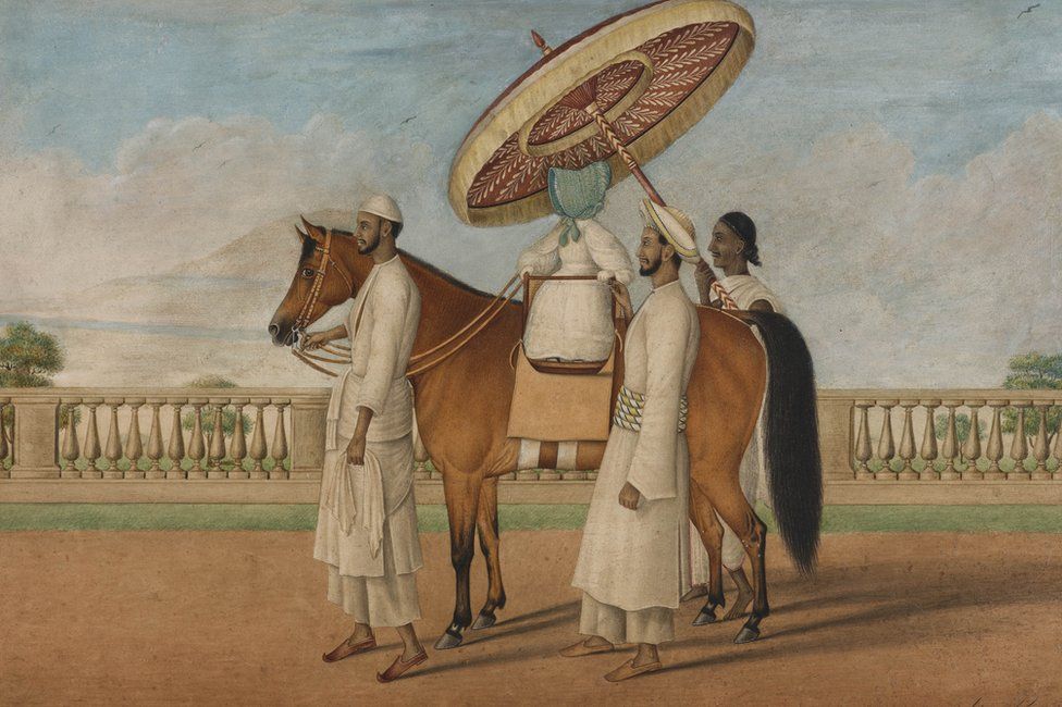 painging from colonial India. A British child rides a pony, surrounded by three adult Indian servants who are leading the hpony and shading the child with a large umbrella