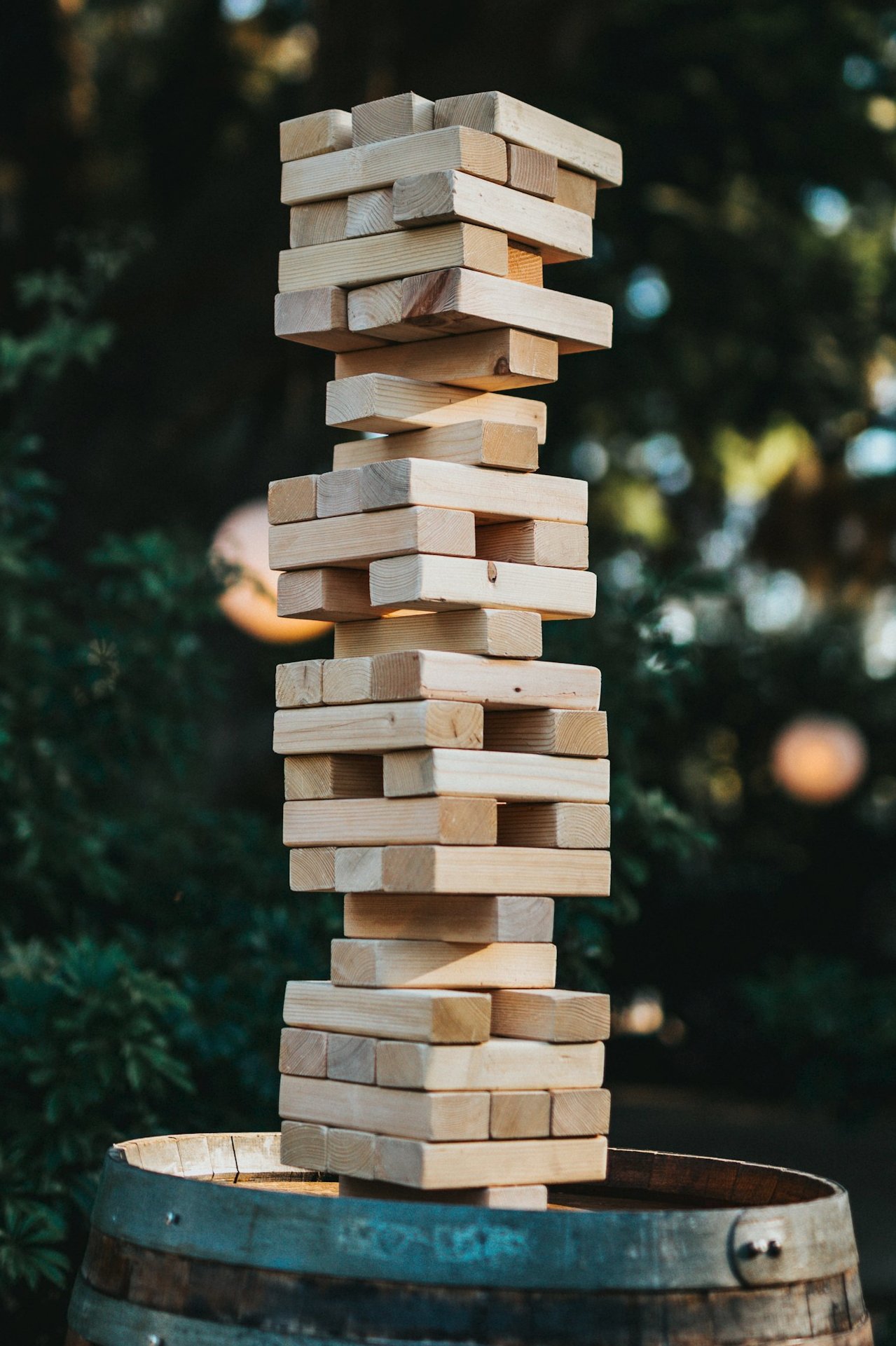 A precarious tower of wooden blocks stacked on top of a barrel. The blocks are arranged as in Jenga.