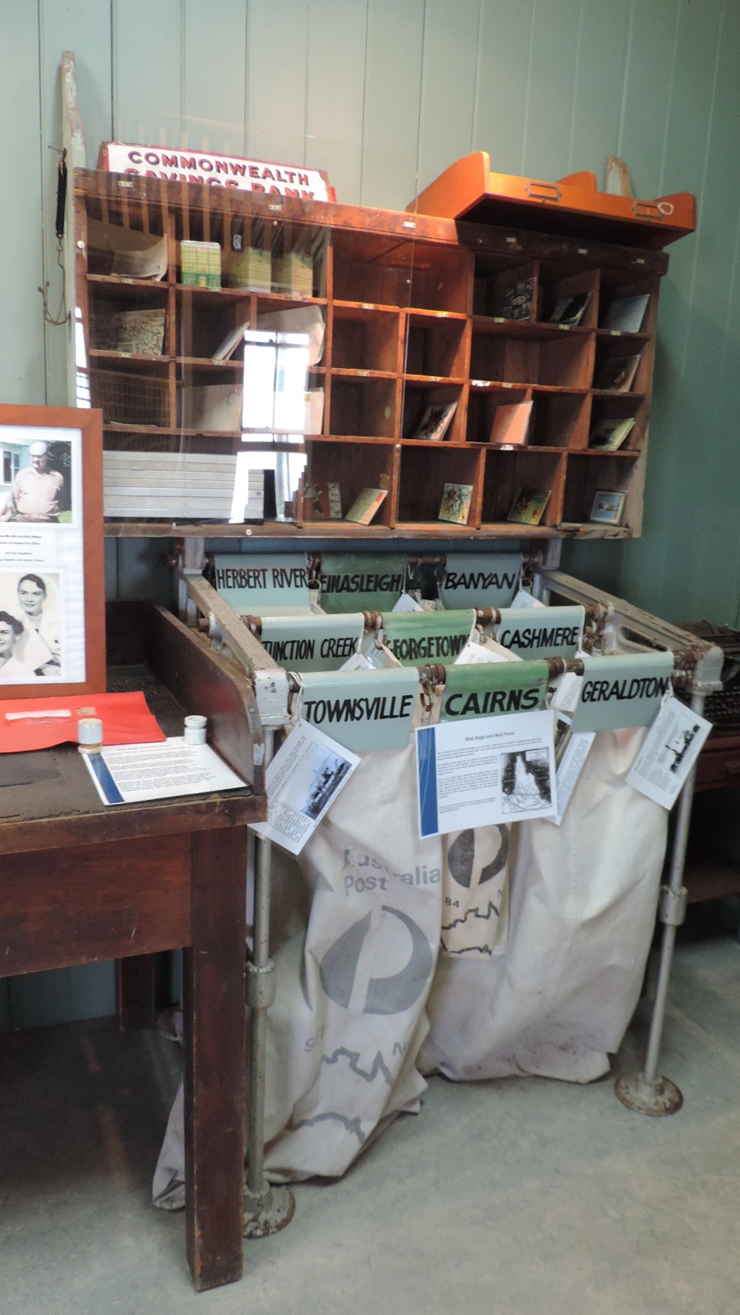 Photo of a small-scale postal sorting station, with large bags labeled with different town names