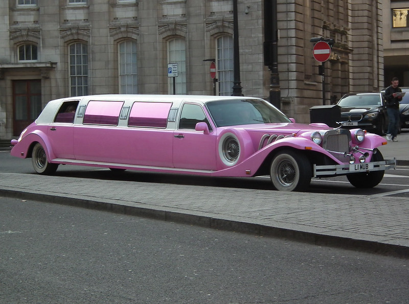 A Pink 'Excalibur' Limo parked on a cobblestone street.