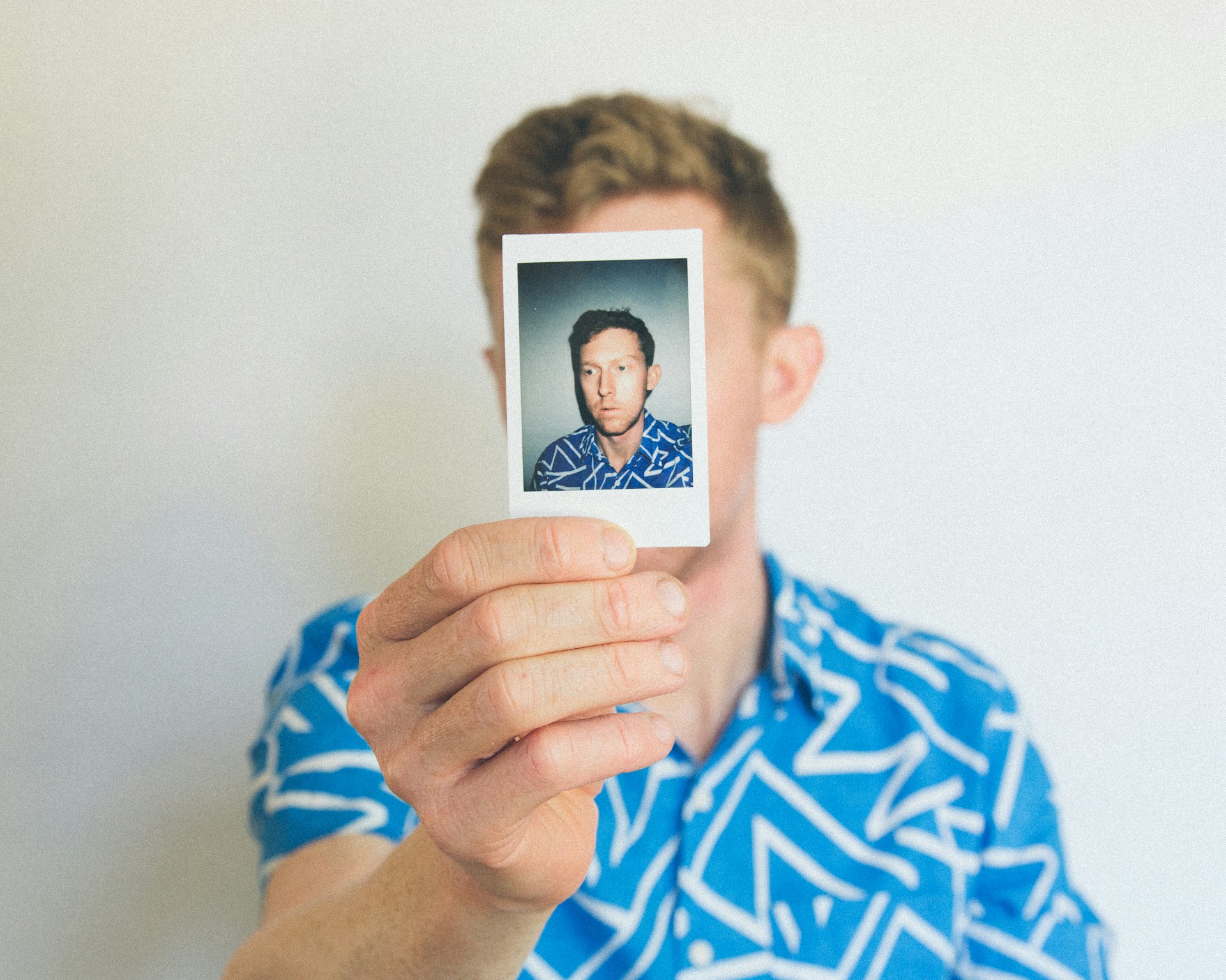 Photo of a man holding a small photo of himself in the same shirt in front of his face