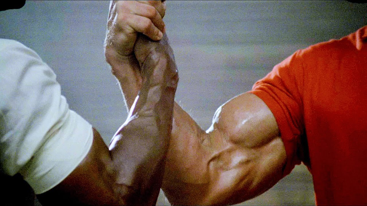 Photo of two extremely muscular arms with their hands tightly gripped together.