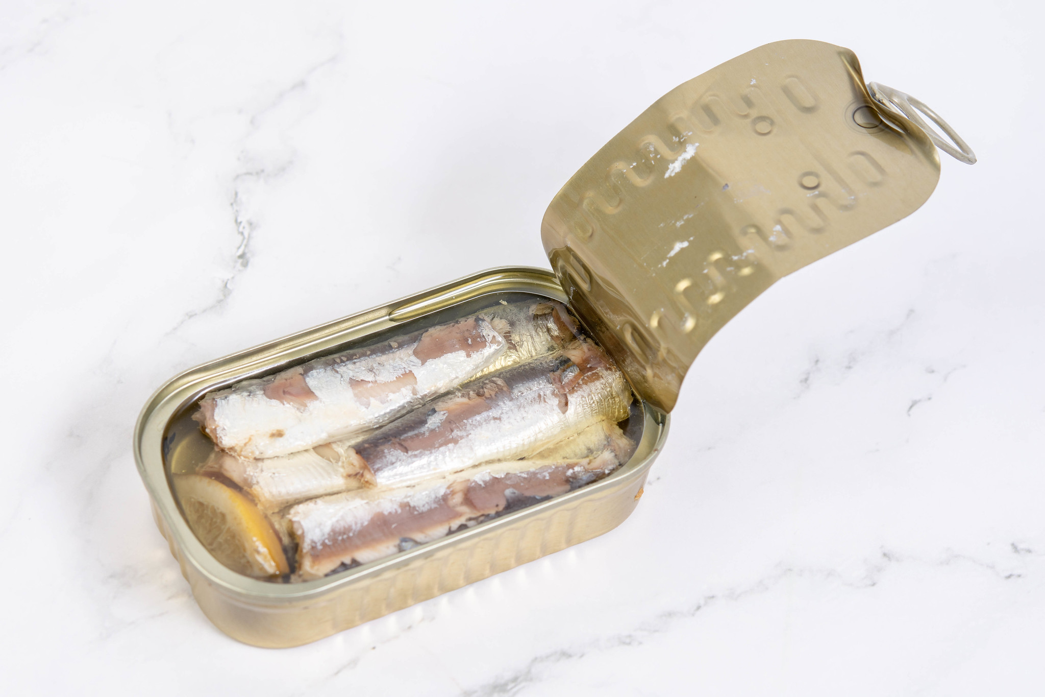 Photo of a tin of sardines with the lid peeled back on a white surface