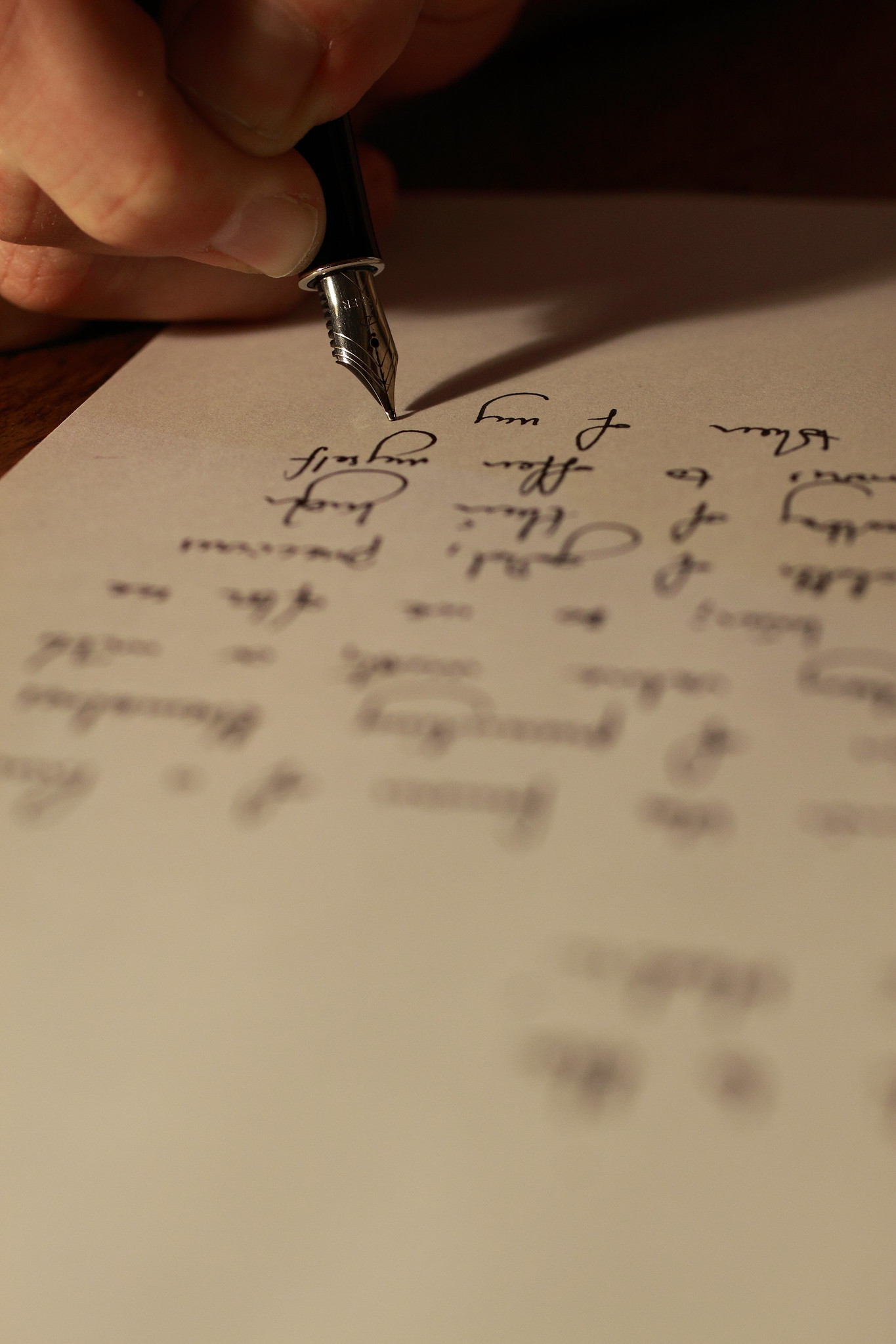 Close up photo of hand writing on a white sheet of paper with a fountain pen